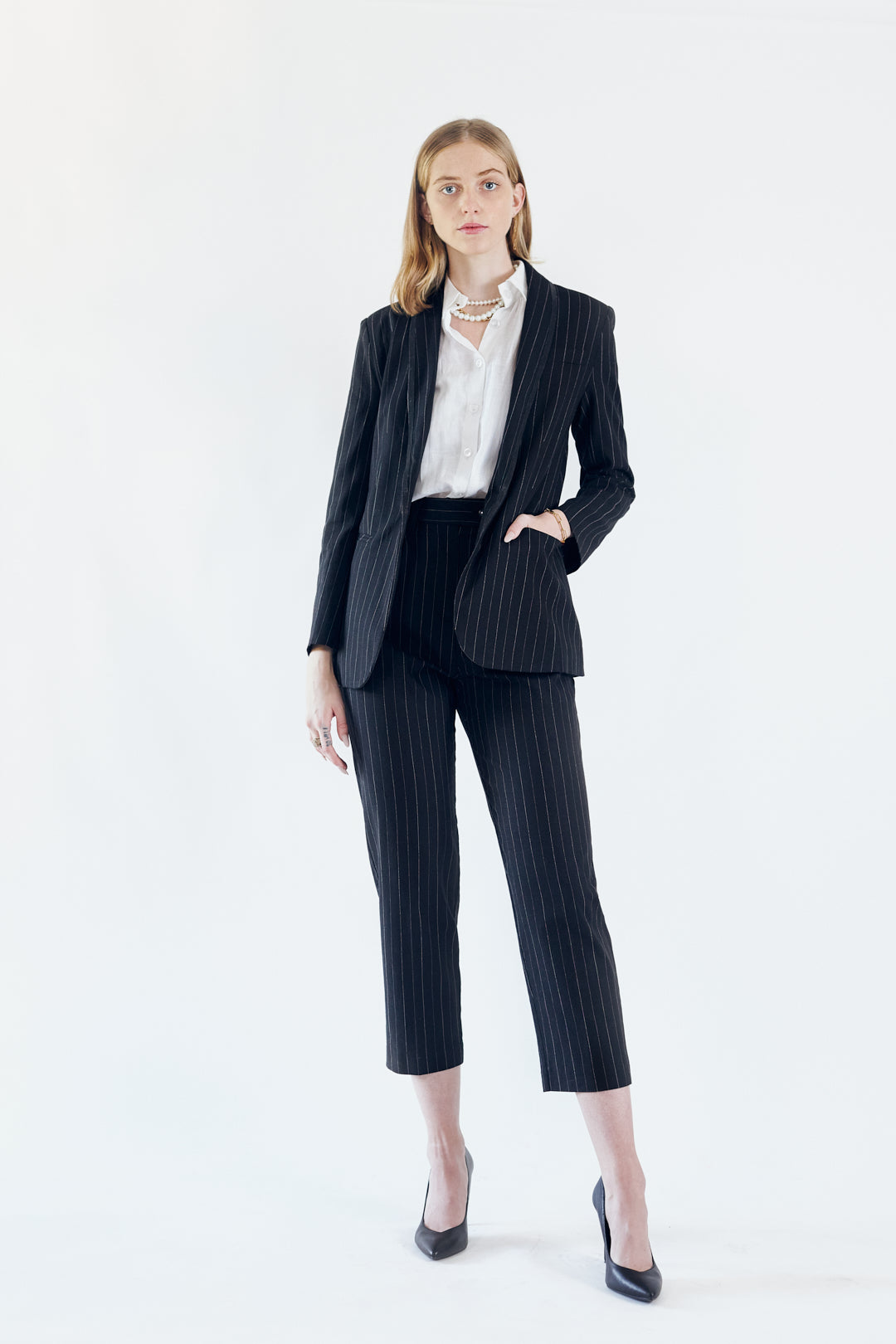 A stylish black blazer with white pinstripes, featuring designed lapels and a single button closure, perfect for professional and casual wear.