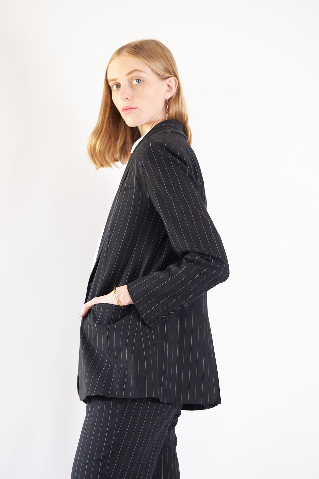 A stylish black blazer with white pinstripes, featuring designed lapels and a single button closure, perfect for professional and casual wear.