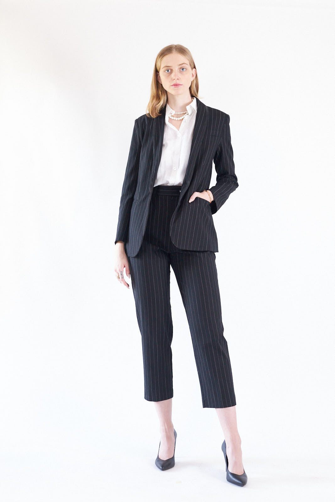 Black pinstripes suit pants with a high-rise waist and slim-straight leg, featuring white stripes on a black background.