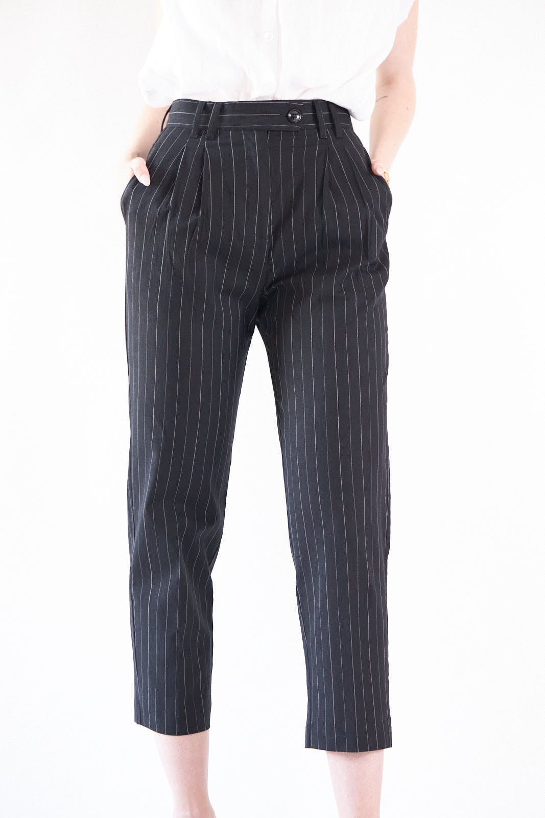 Black pinstripes suit pants with a high-rise waist and slim-straight leg, featuring white stripes on a black background.