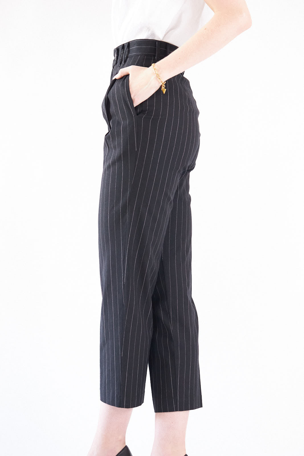 Black pinstripes suit pants with a high-rise waist and slim-straight leg, featuring white stripes on a black background.