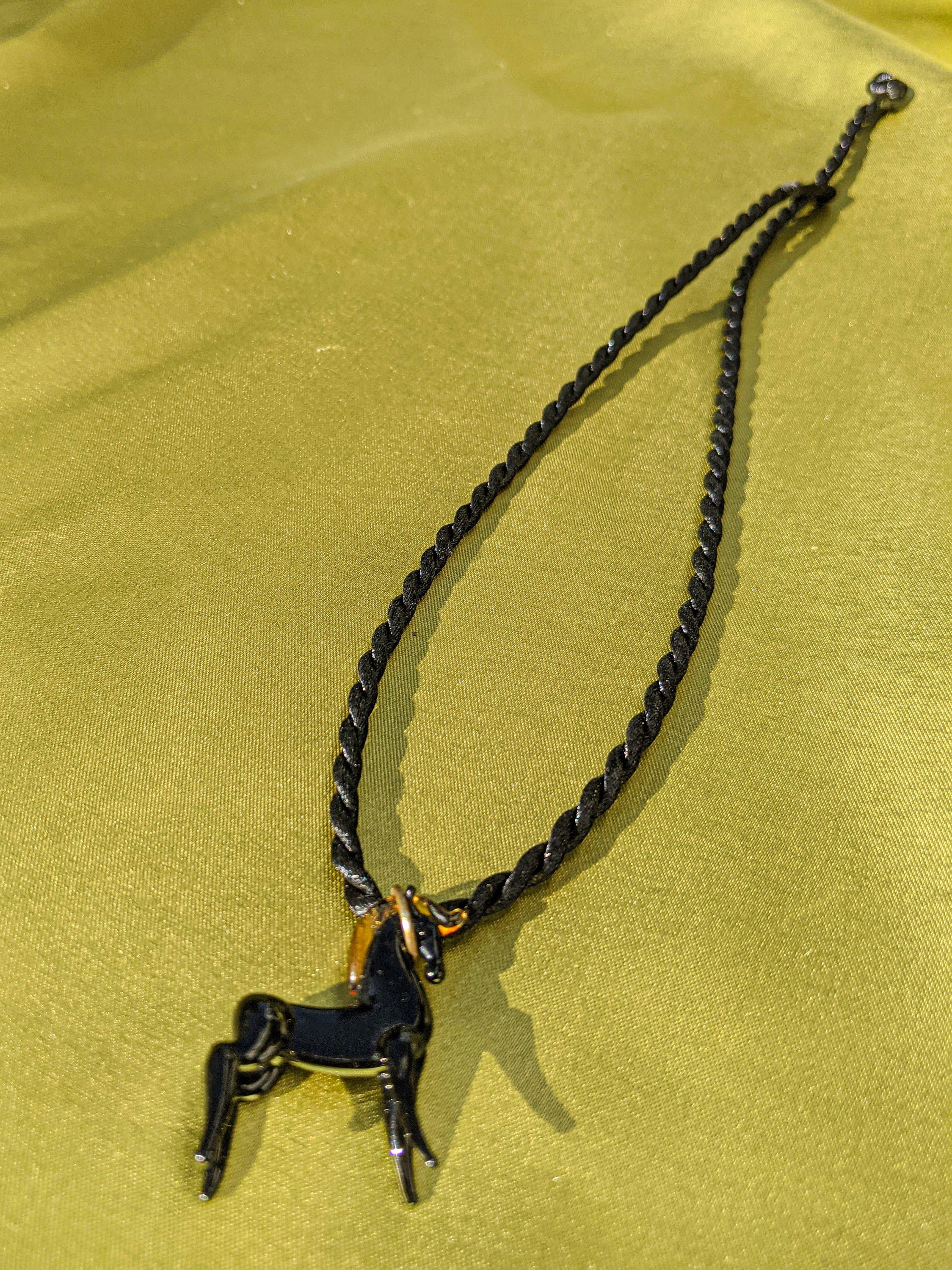 A stylish black rope necklace featuring a beautifully crafted glass horse pendant, showcasing intricate details.