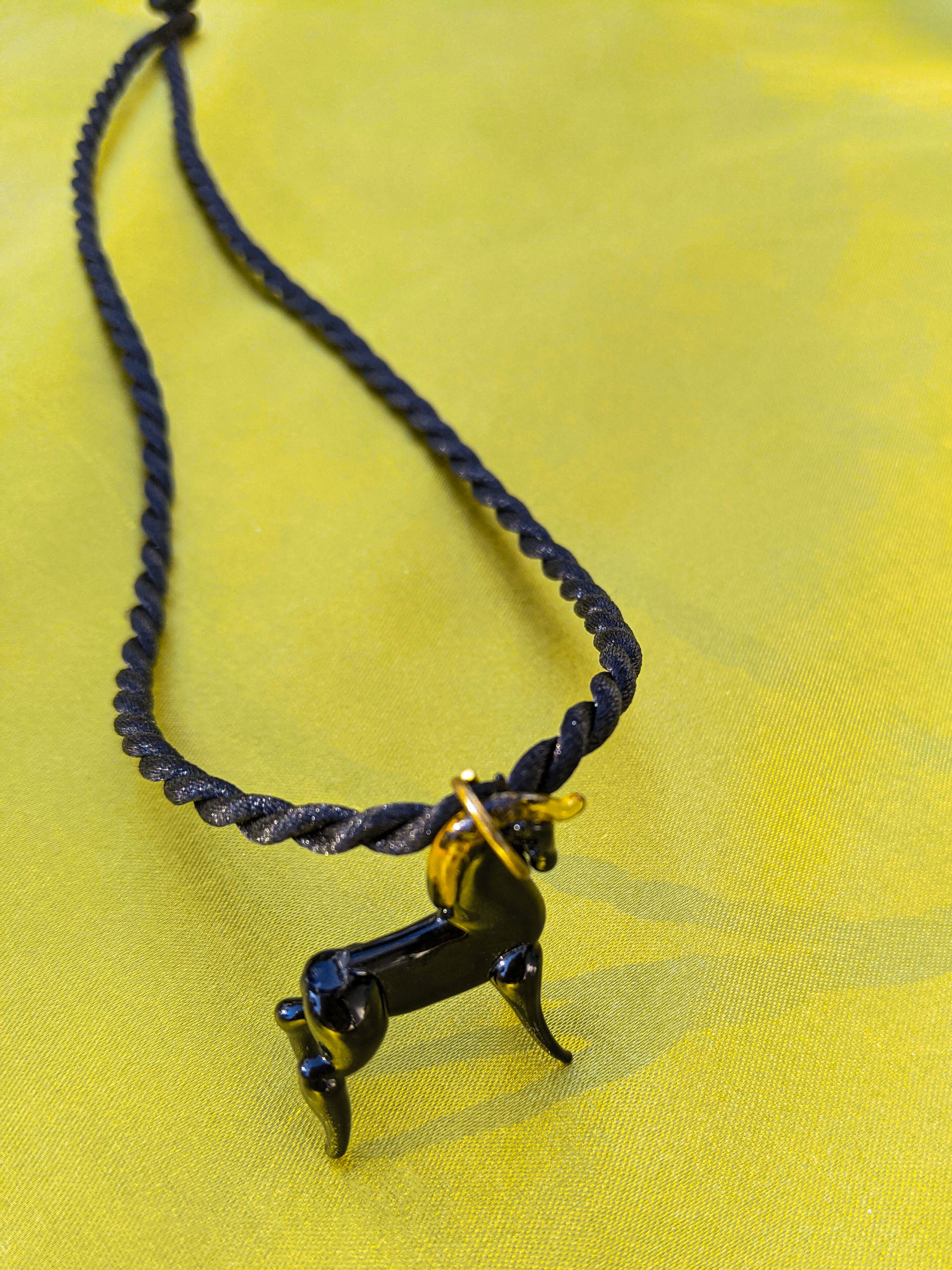 A stylish black rope necklace featuring a beautifully crafted glass horse pendant, showcasing intricate details.