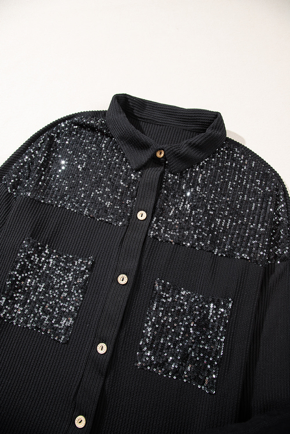 Black corded shacket featuring a sequin patch on the chest pocket, designed for casual wear with long sleeves.