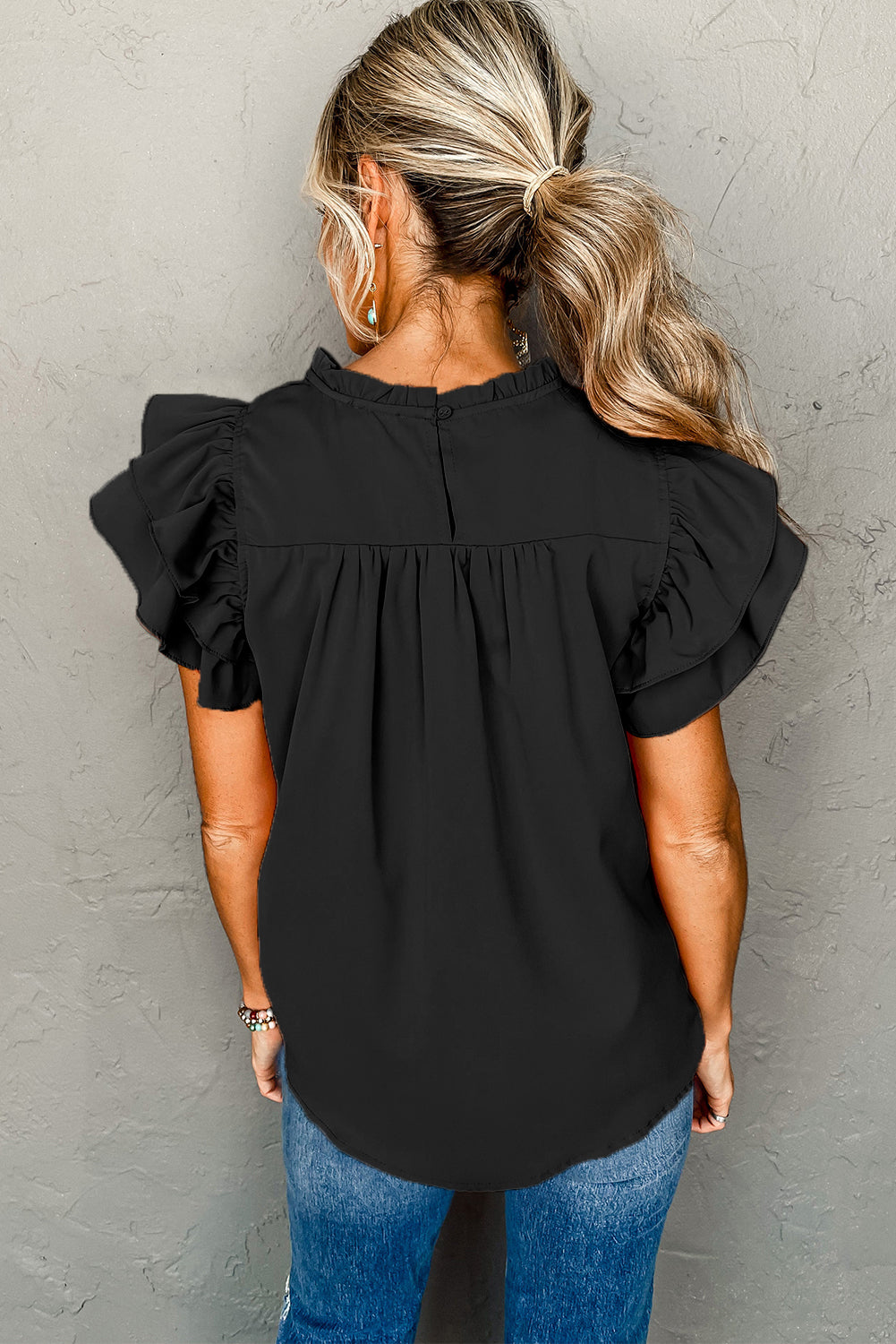 Black smocked ruffle sleeve blouse displayed on a mannequin, showcasing its elegant design and feminine details.