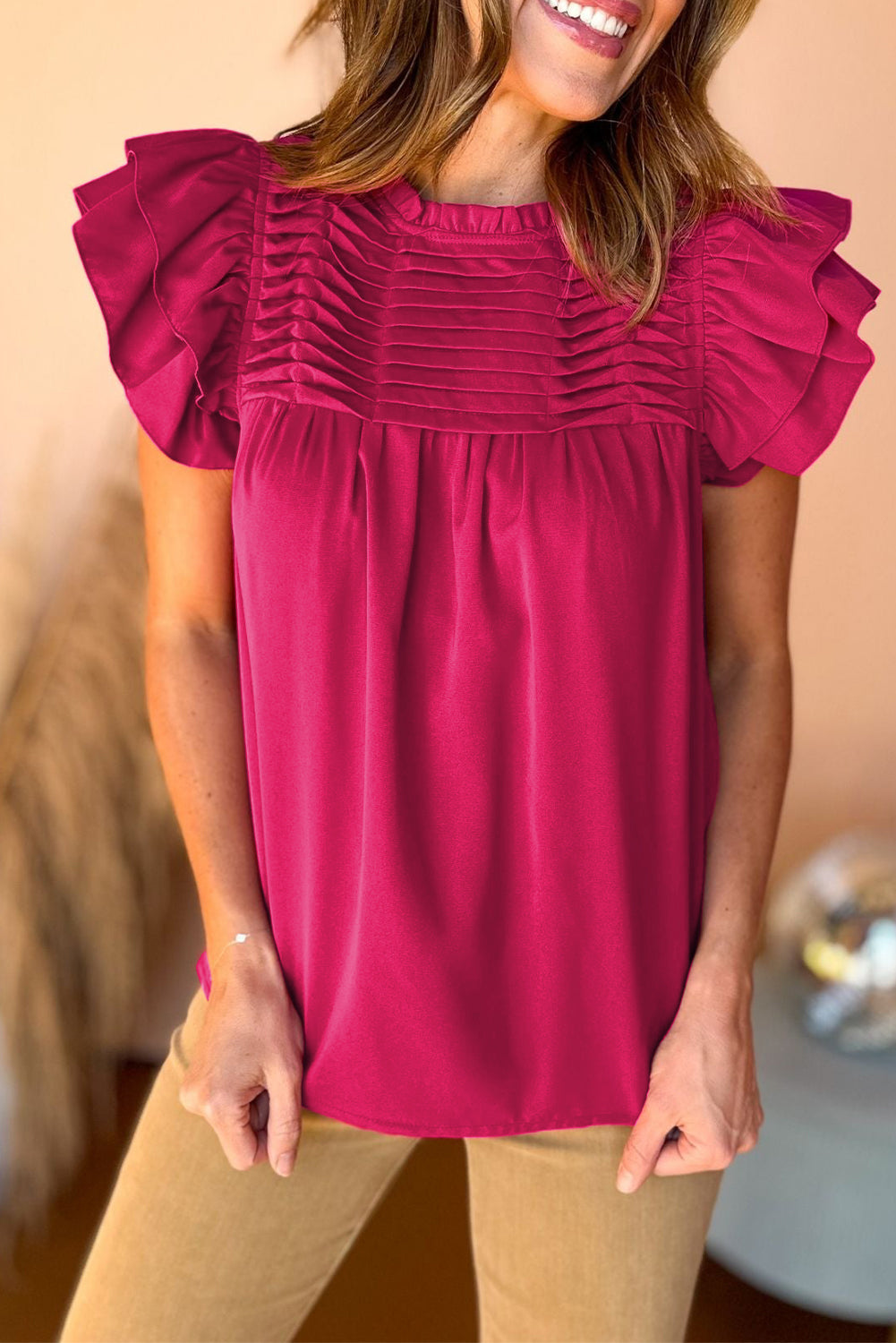 Black smocked ruffle sleeve blouse displayed on a mannequin, showcasing its elegant design and feminine details.