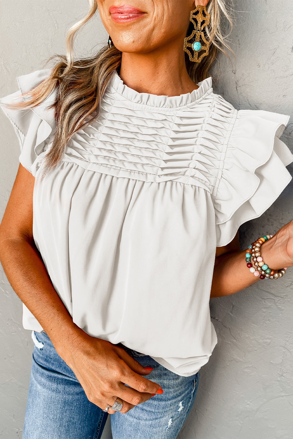 Black smocked ruffle sleeve blouse displayed on a mannequin, showcasing its elegant design and feminine details.