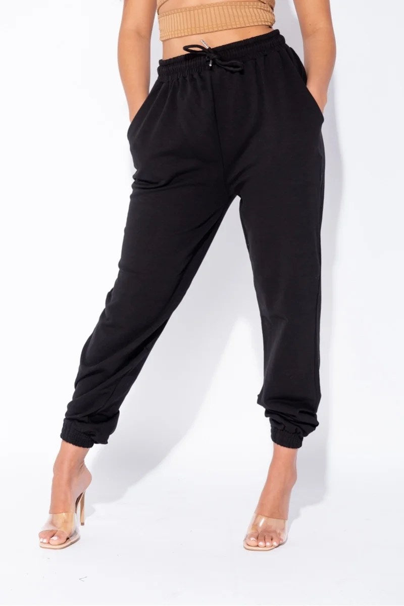 Black oversized joggers with a tie waist, featuring front pockets and a relaxed fit, perfect for casual wear.