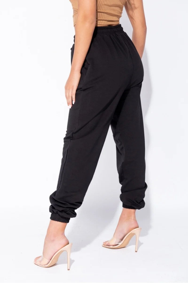 Black oversized joggers with a tie waist, featuring front pockets and a relaxed fit, perfect for casual wear.