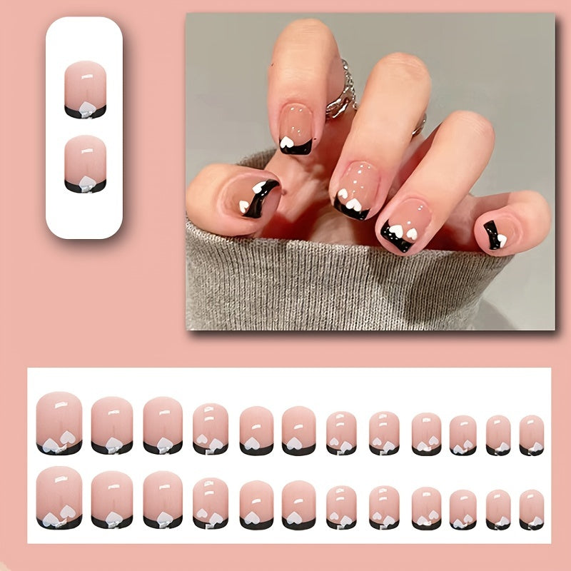 A set of Black & White Heart Nails featuring a shimmery finish and elegant oval shape, adorned with charming heart patterns.