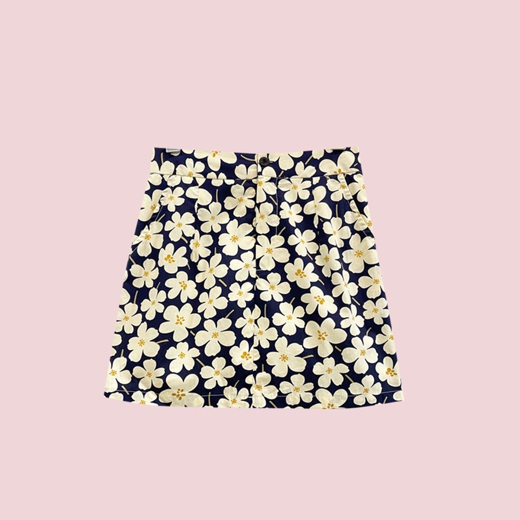 A stylish Blooming Skort featuring floral motifs, soft silk lining, and decorative heart button straps, perfect for warm weather.