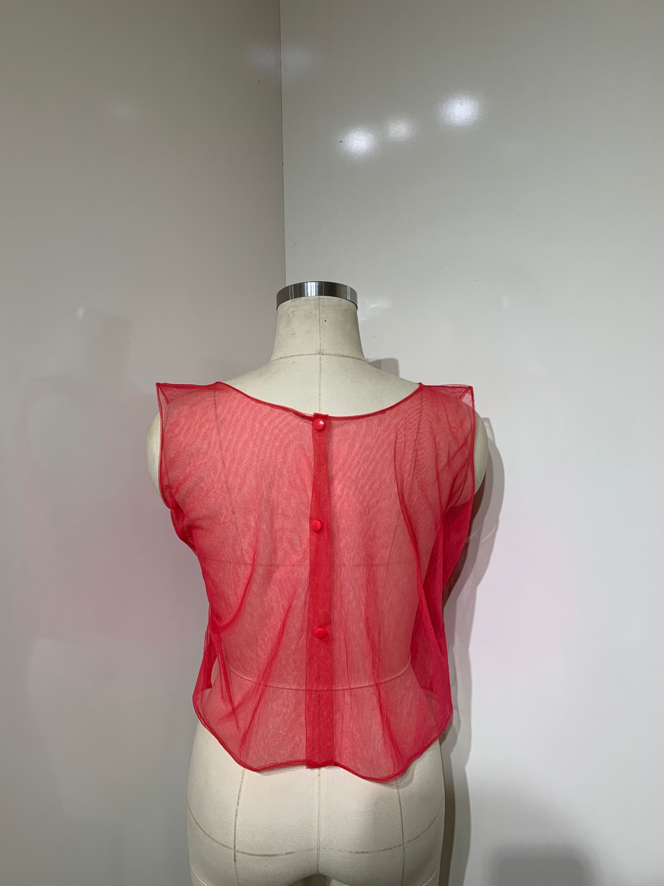 A vibrant red sheer tulle top featuring a playful ruffled flower detail at the center, perfect for stylish occasions.