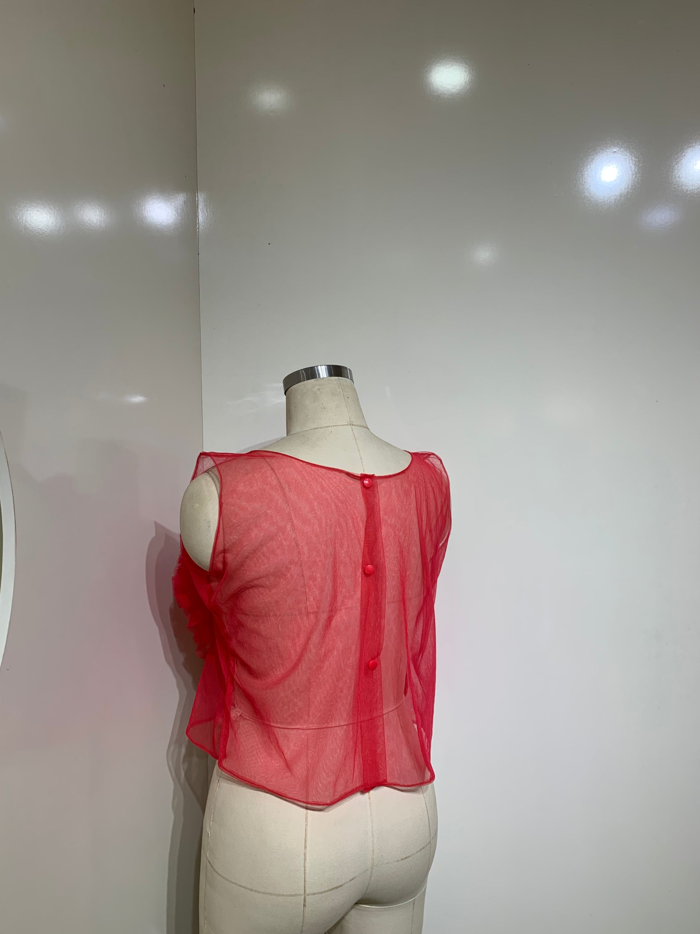 A vibrant red sheer tulle top featuring a playful ruffled flower detail at the center, perfect for stylish occasions.