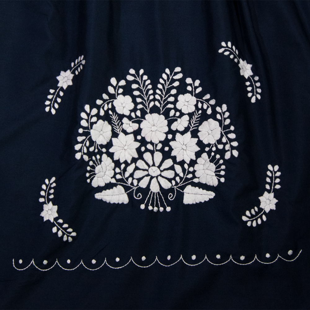 A beautiful navy blue dress adorned with white flowers, showcasing intricate hand embroidery, perfect for bohemian style.