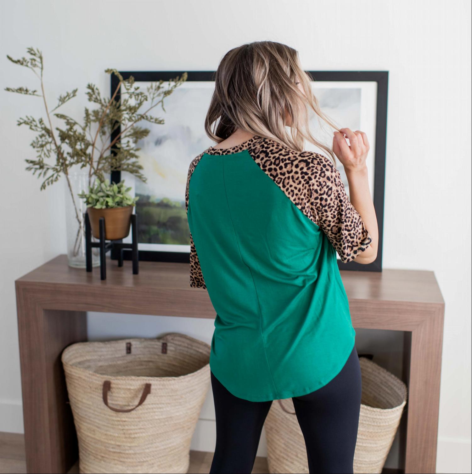 A stylish Bold Leopard Print Blouse featuring a relaxed fit, elbow-length sleeves, and a large chest pocket, with vibrant colors and leopard print details.