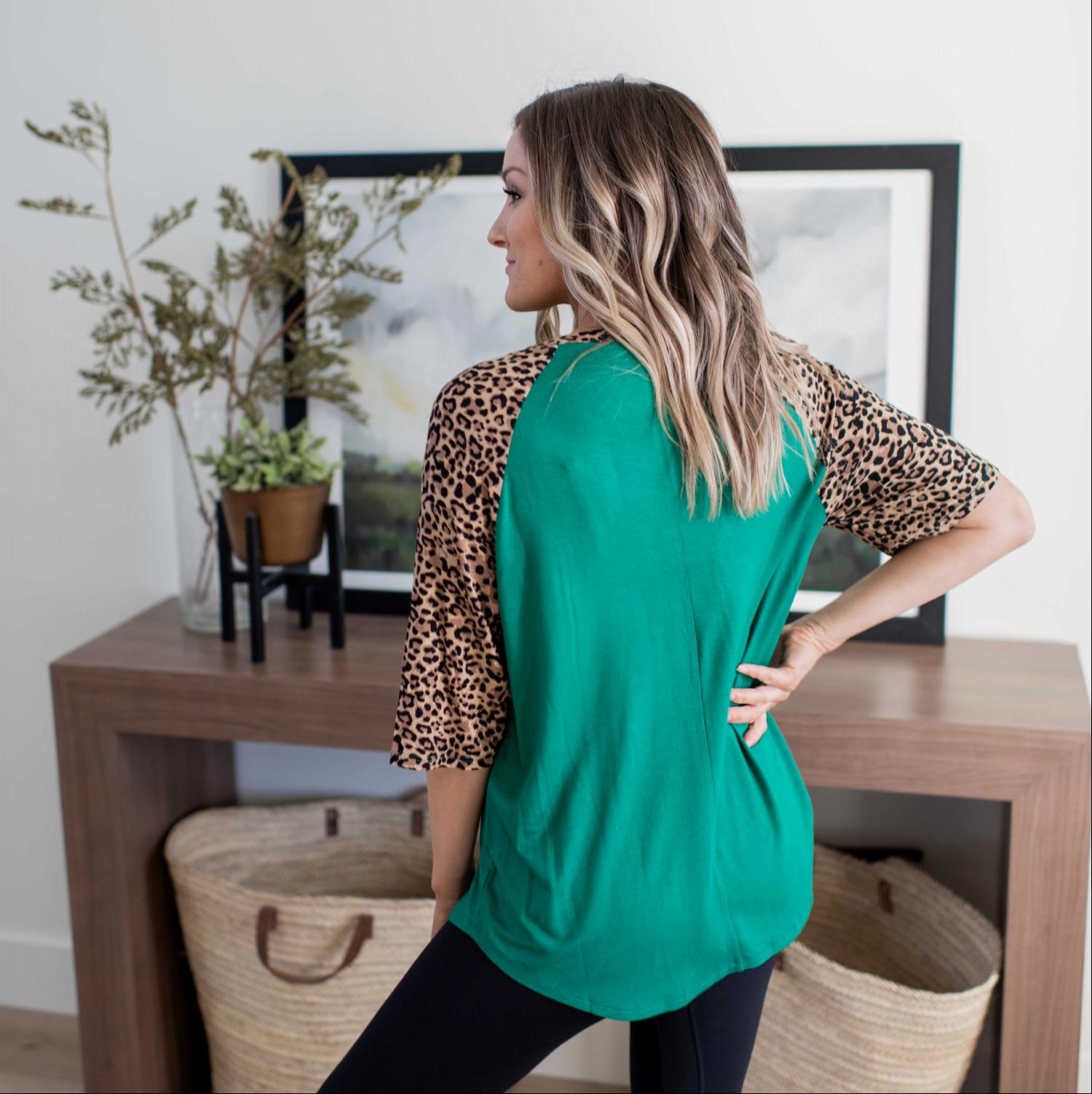 A stylish Bold Leopard Print Blouse featuring a relaxed fit, elbow-length sleeves, and a large chest pocket, with vibrant colors and leopard print details.