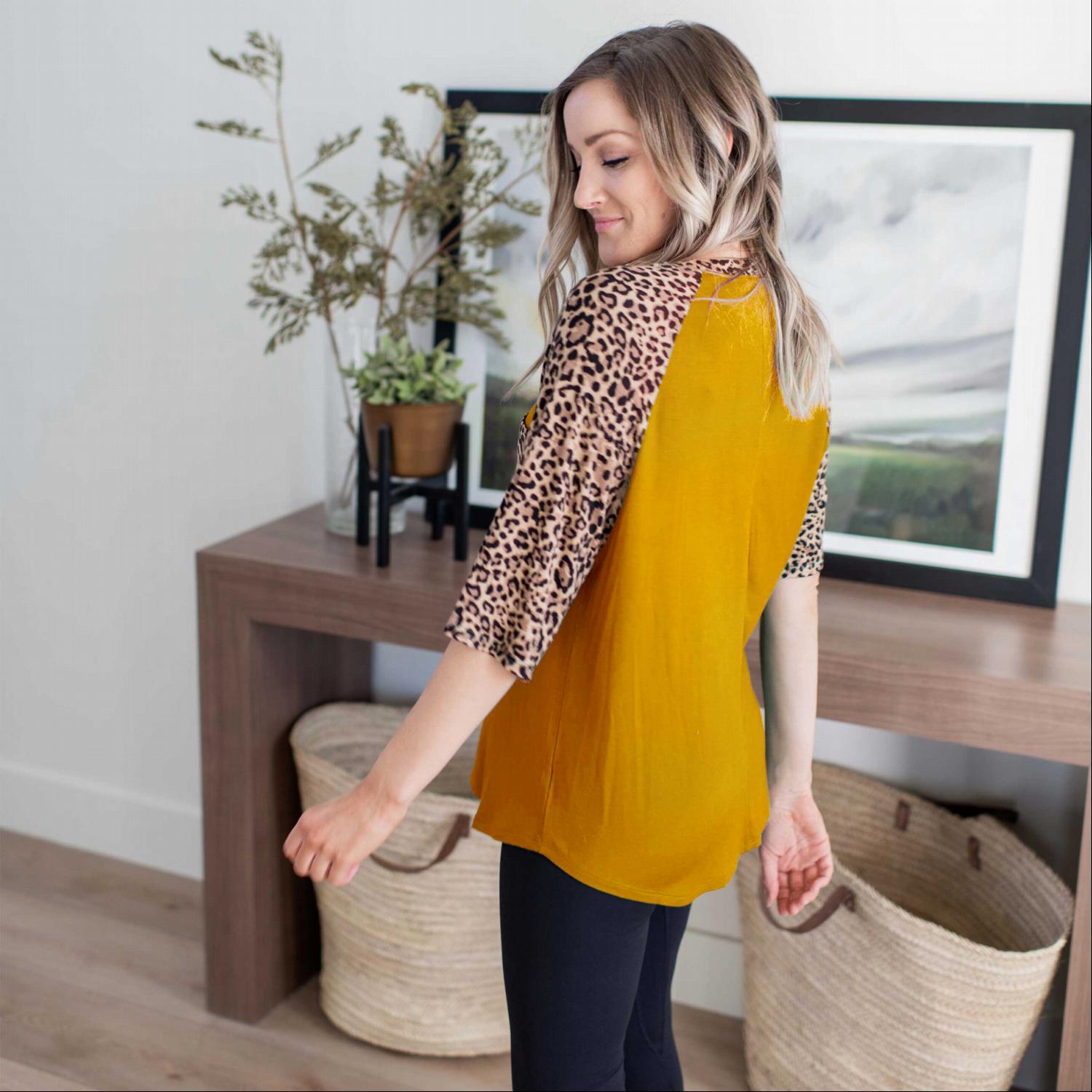 A stylish Bold Leopard Print Blouse featuring a relaxed fit, elbow-length sleeves, and a large chest pocket, with vibrant colors and leopard print details.