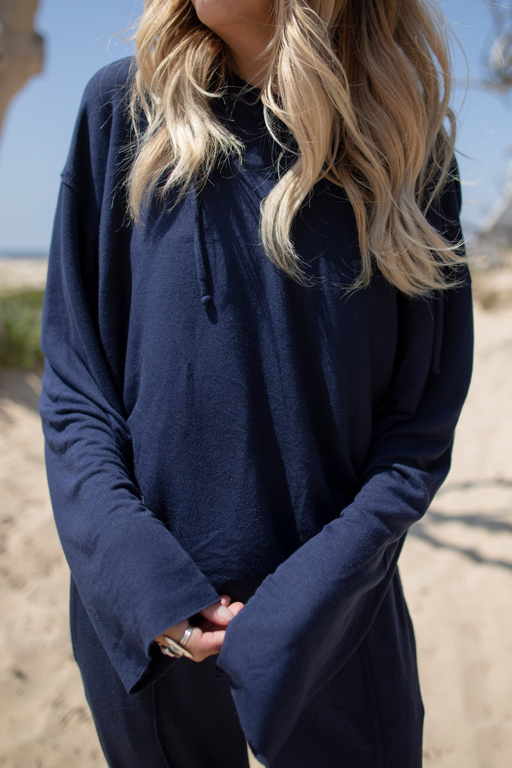 A stylish Boxy Hoodie featuring raw hems, exposed stitching, and a cropped fit, made from organic cotton and Tencel.