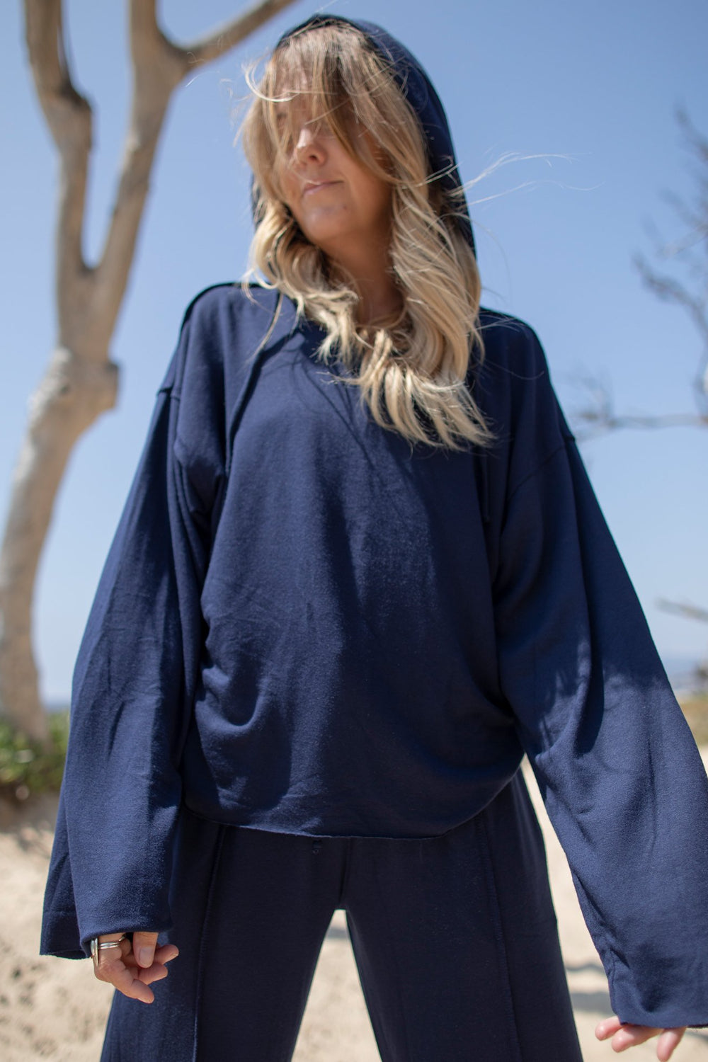 A stylish Boxy Hoodie featuring raw hems, exposed stitching, and a cropped fit, made from organic cotton and Tencel.