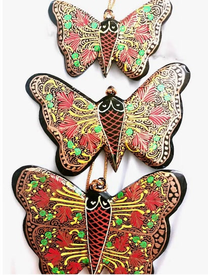 A collection of beautifully hand-painted butterly shaped holiday ornaments, showcasing vibrant colors and intricate designs, crafted from recycled paper.