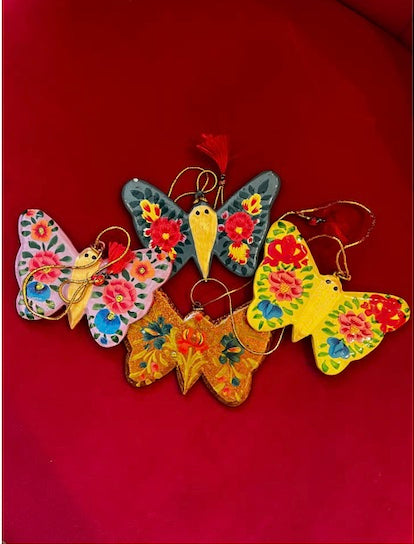 A collection of beautifully hand-painted butterly shaped holiday ornaments, showcasing vibrant colors and intricate designs, crafted from recycled paper.