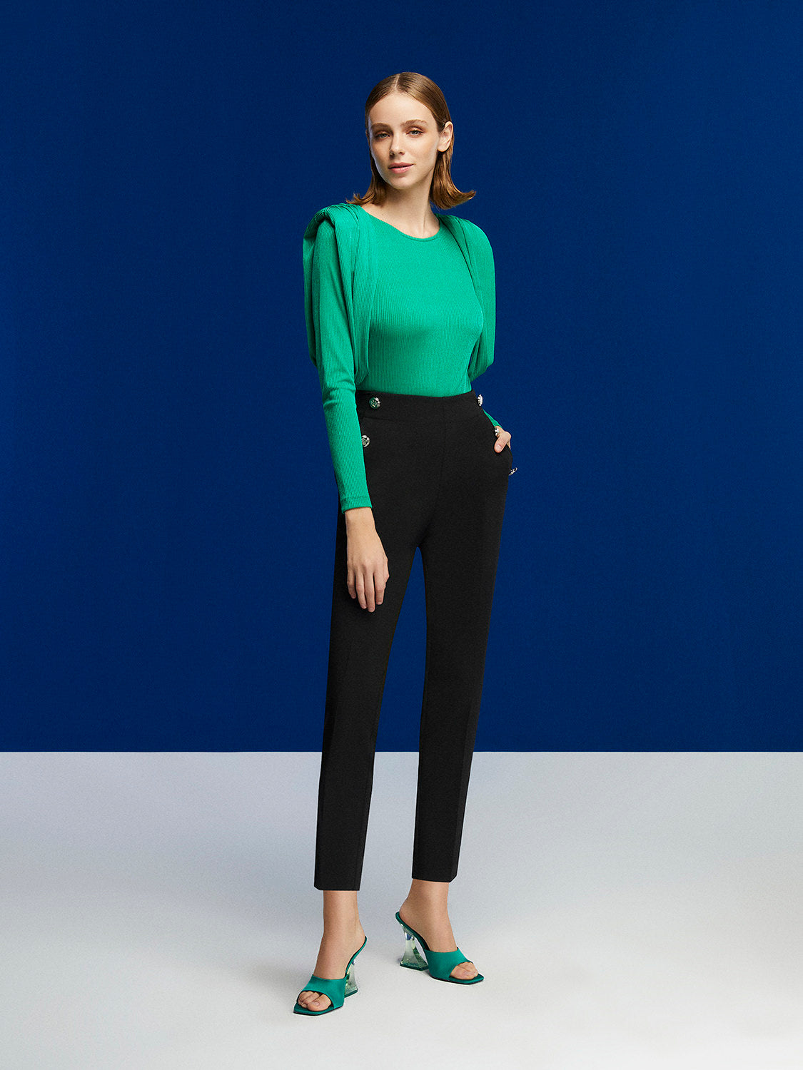 High-waisted ankle-length pants with button details and pockets, showcasing a stylish design.