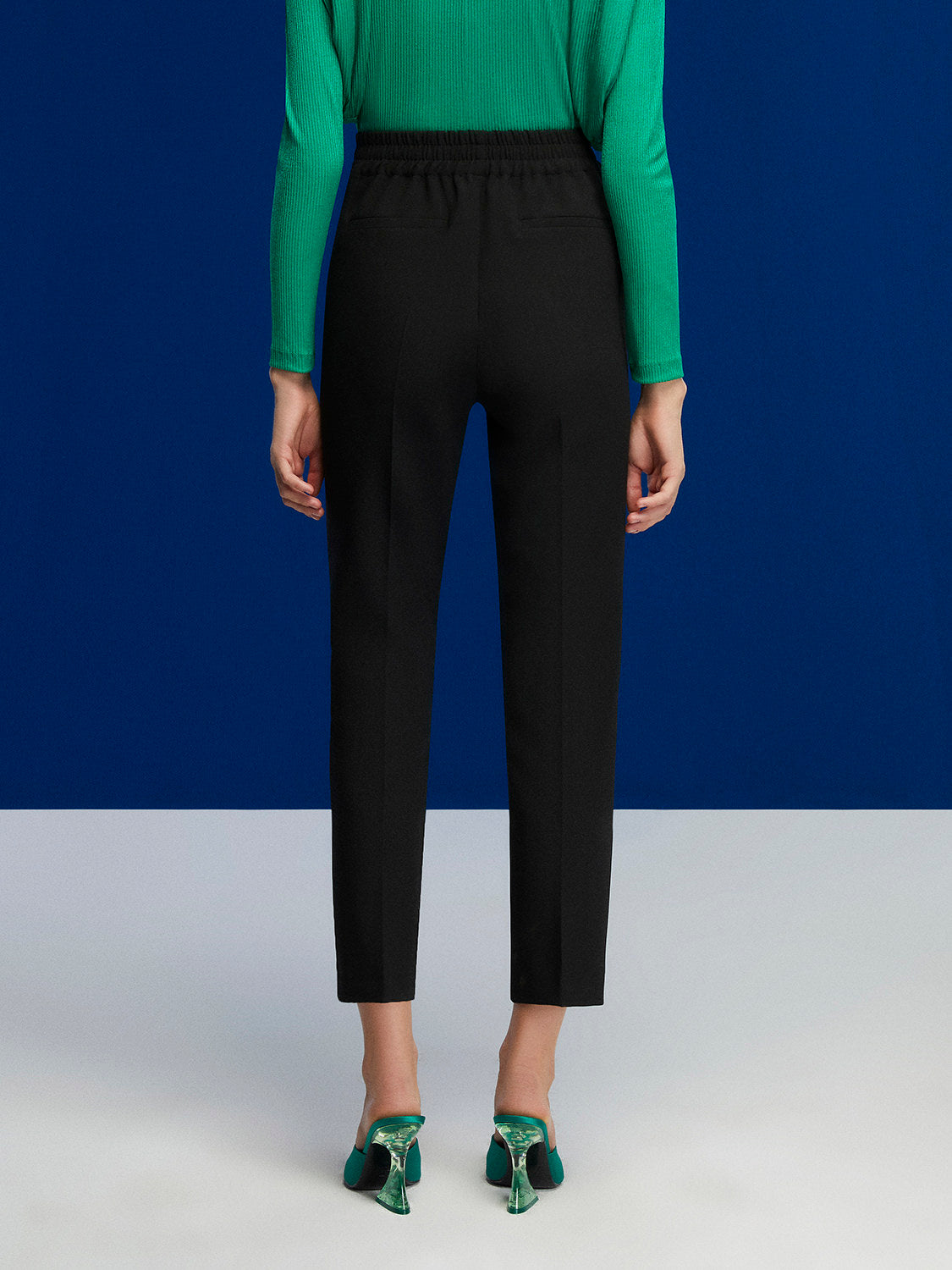 High-waisted ankle-length pants with button details and pockets, showcasing a stylish design.