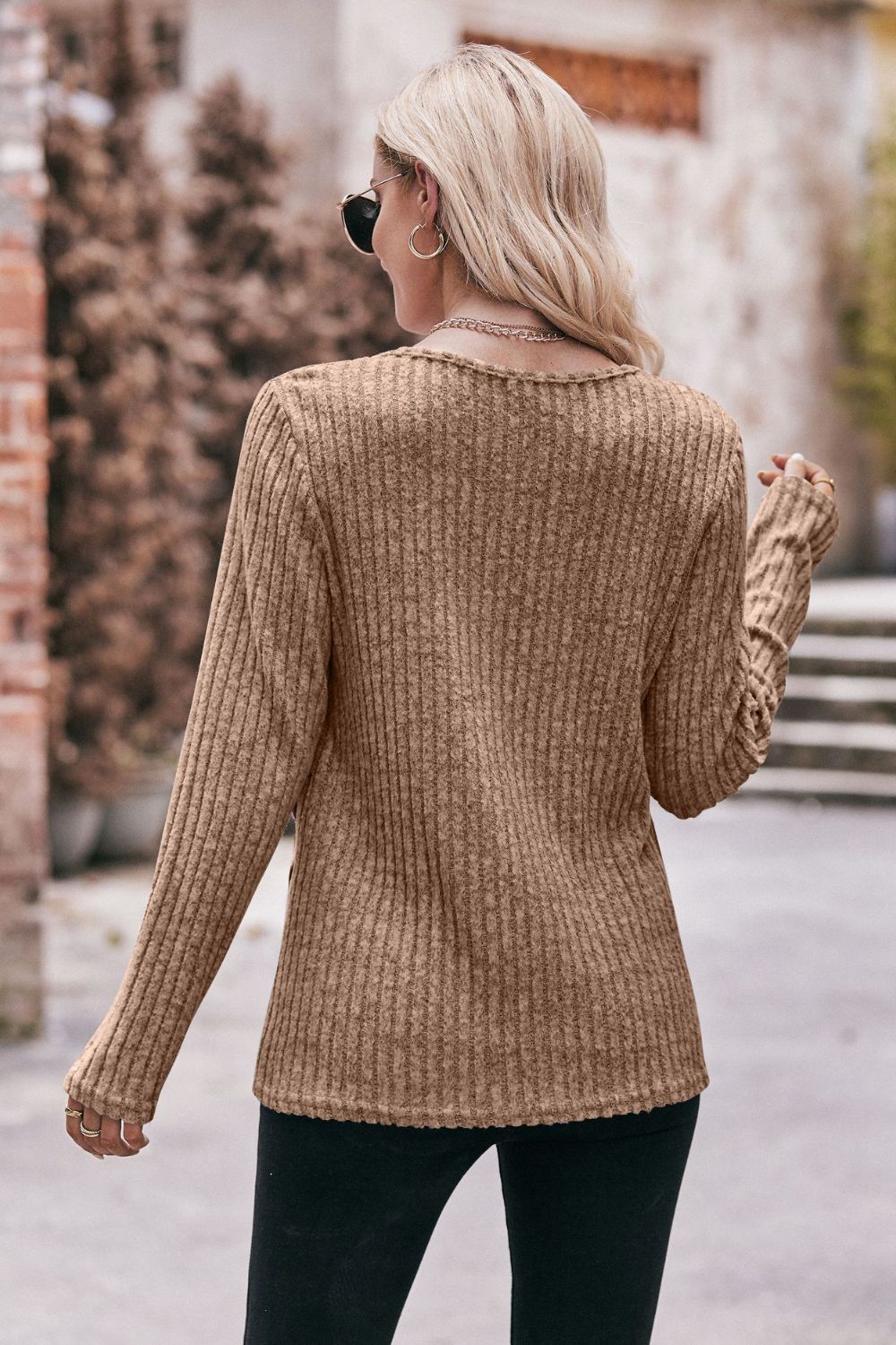 A stylish Buttoned Hem Detail Ribbed Top featuring a round neck, long sleeves, and a unique buttoned hem design in a solid color.