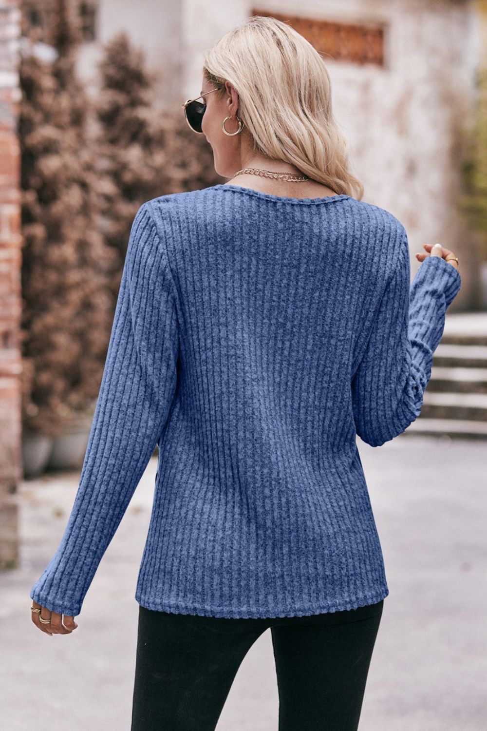 A stylish Buttoned Hem Detail Ribbed Top featuring a round neck, long sleeves, and a unique buttoned hem design in a solid color.