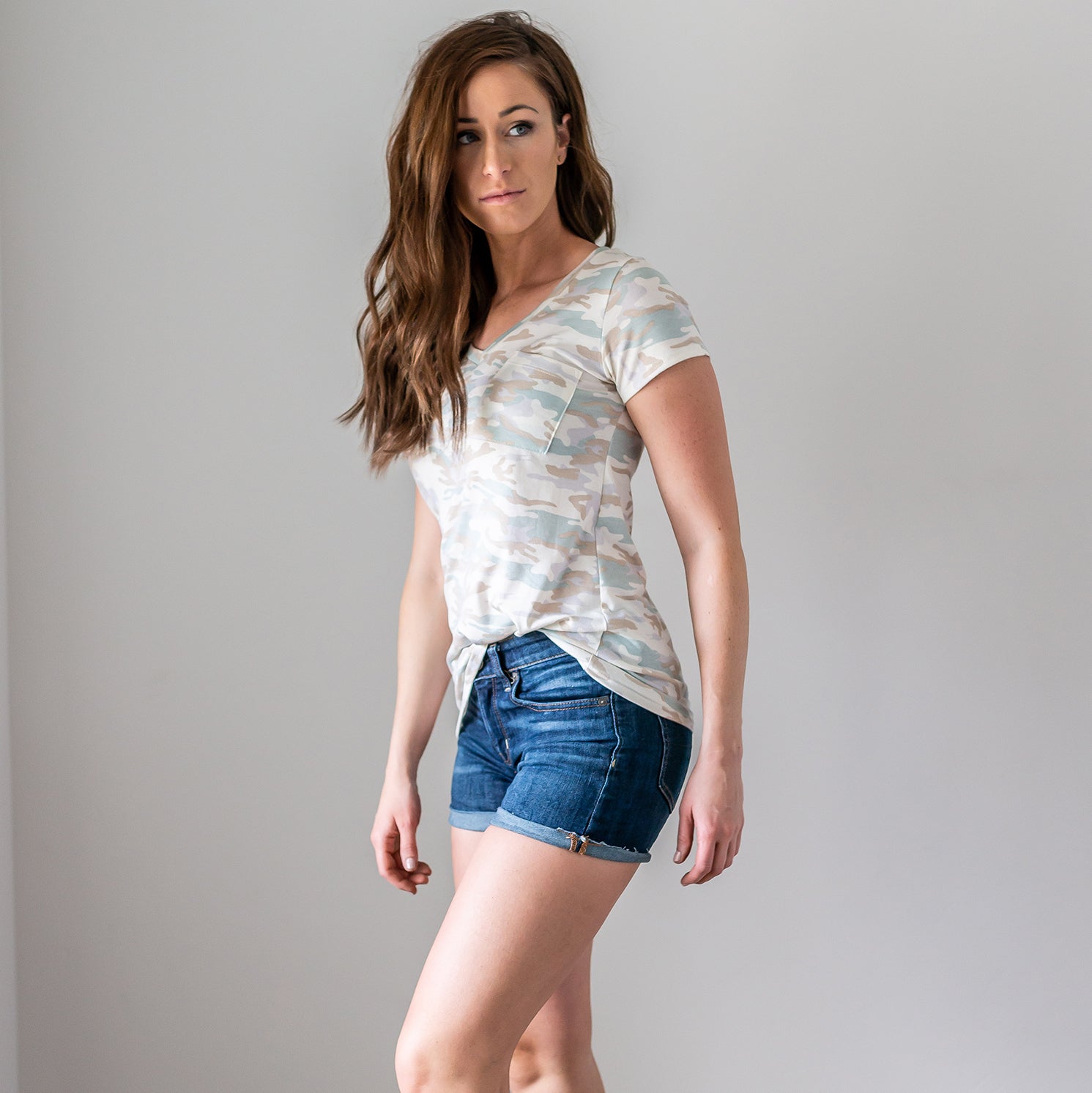 A stylish Camo V-Neck Top featuring a light camo print, short sleeves, and a front pocket, perfect for casual wear or as a beach cover-up.