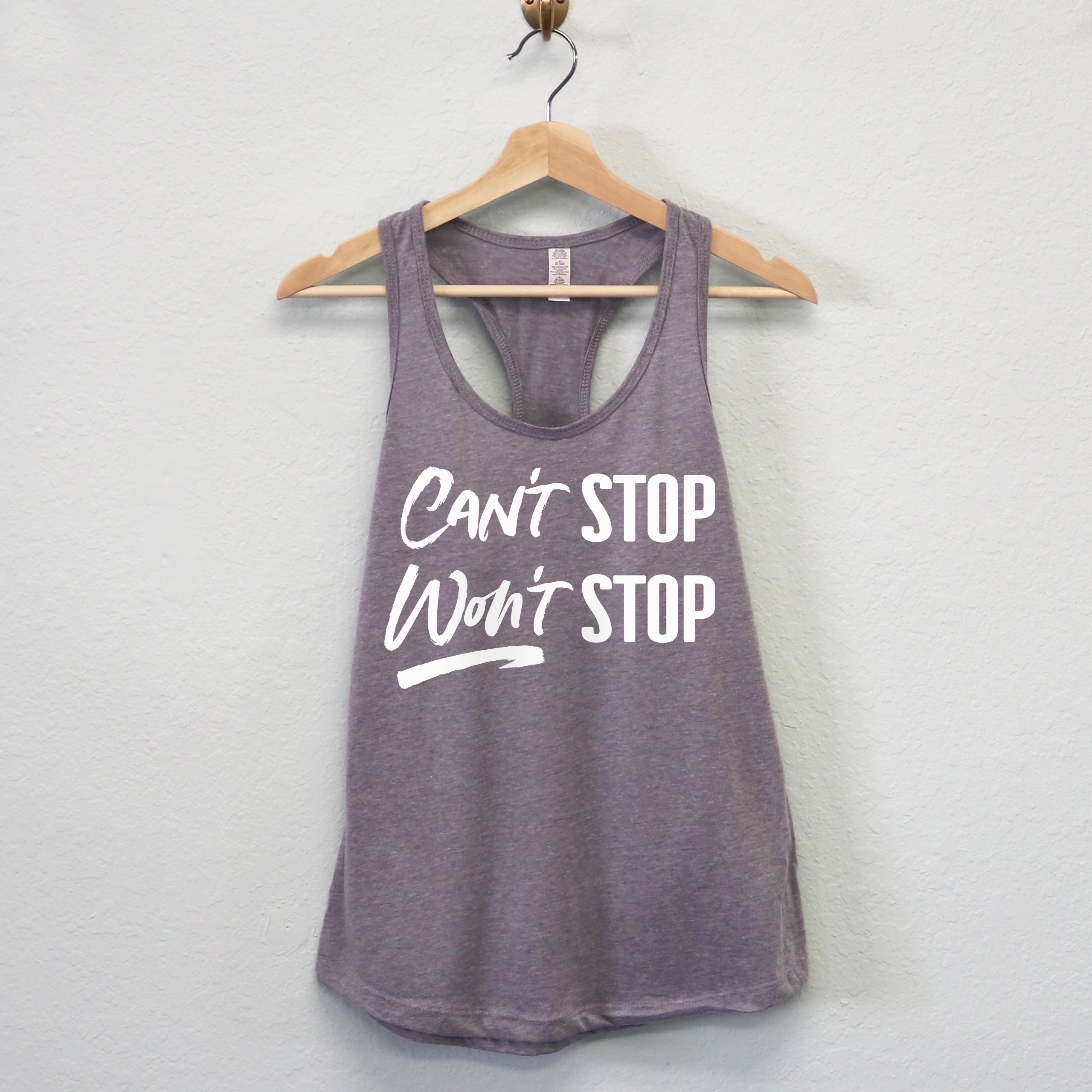 A stylish women's workout tank top featuring the motivational phrase 'CAN'T STOP WON'T STOP' in a racerback design, available in multiple colors.