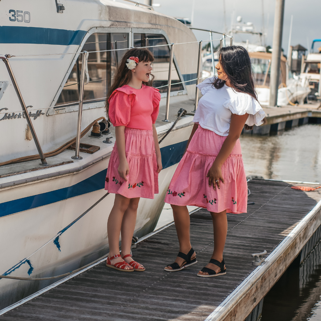 The Cari Skirt featuring intricate hand embroidery on pink chambray fabric, showcasing traditional artisan craftsmanship from Oaxaca, Mexico.