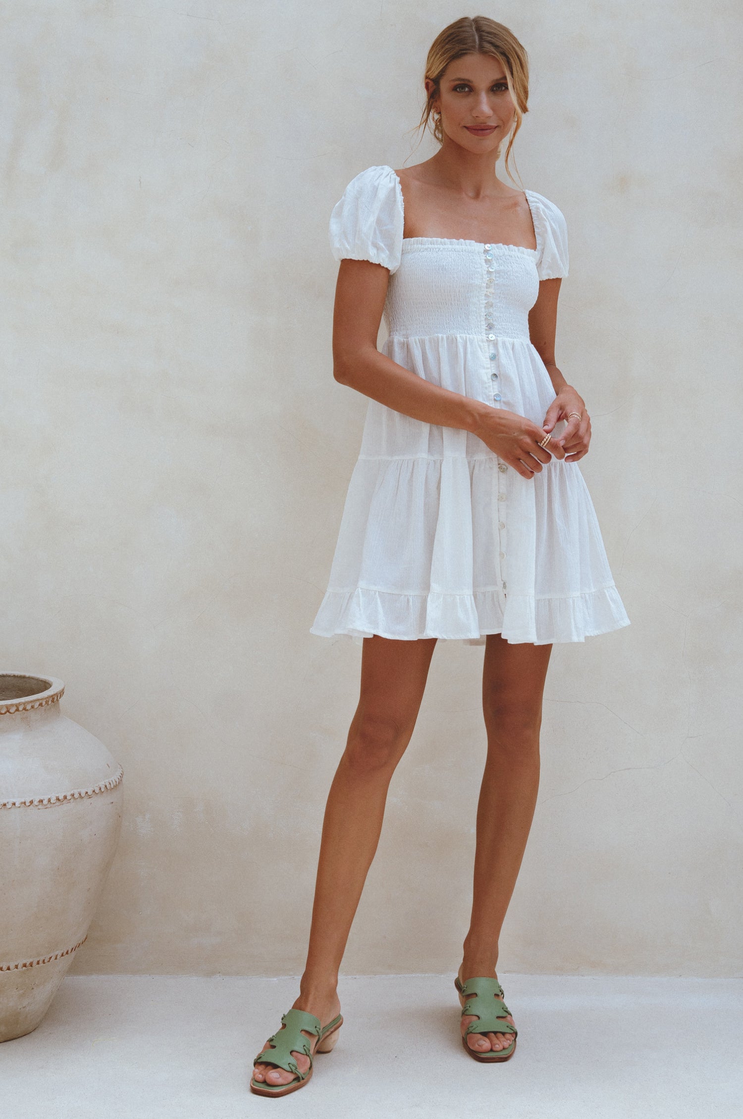 A stylish Catalina Smocked Linen Mini Dress featuring a smocked bodice, ruffles, and petite shell buttons, made from breathable organic linen.