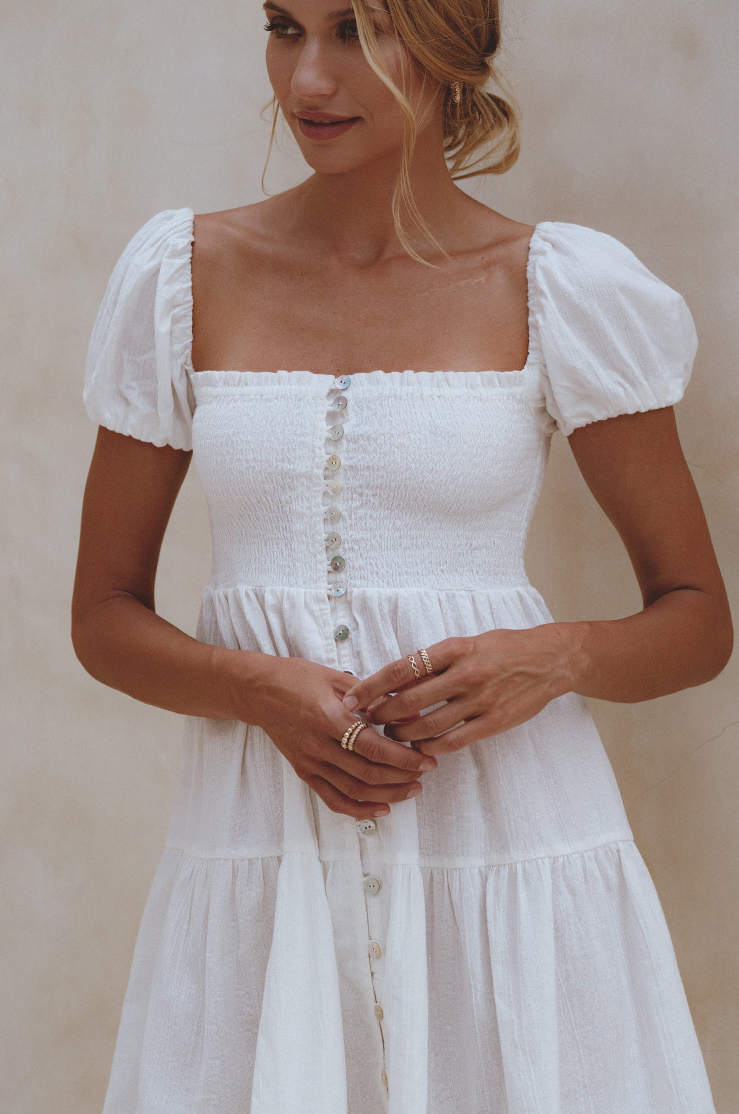 A stylish Catalina Smocked Linen Mini Dress featuring a smocked bodice, ruffles, and petite shell buttons, made from breathable organic linen.