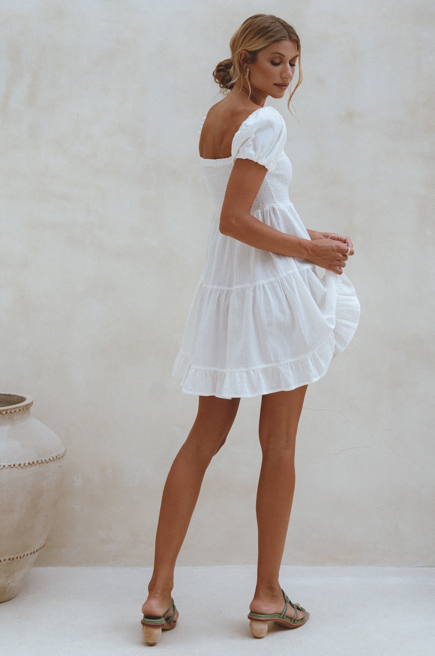 A stylish Catalina Smocked Linen Mini Dress featuring a smocked bodice, ruffles, and petite shell buttons, made from breathable organic linen.