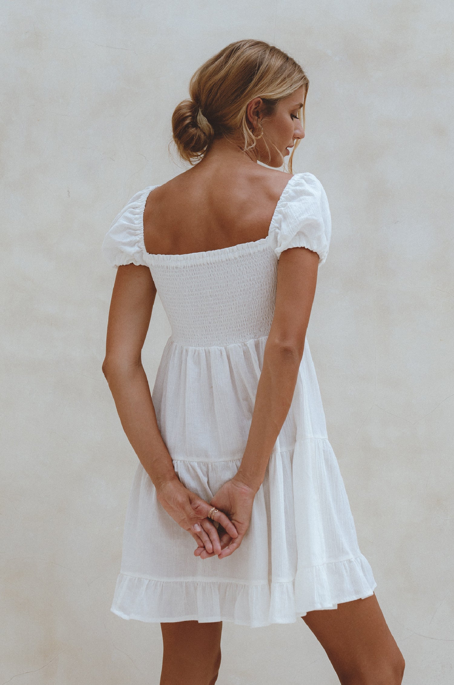 A stylish Catalina Smocked Linen Mini Dress featuring a smocked bodice, ruffles, and petite shell buttons, made from breathable organic linen.