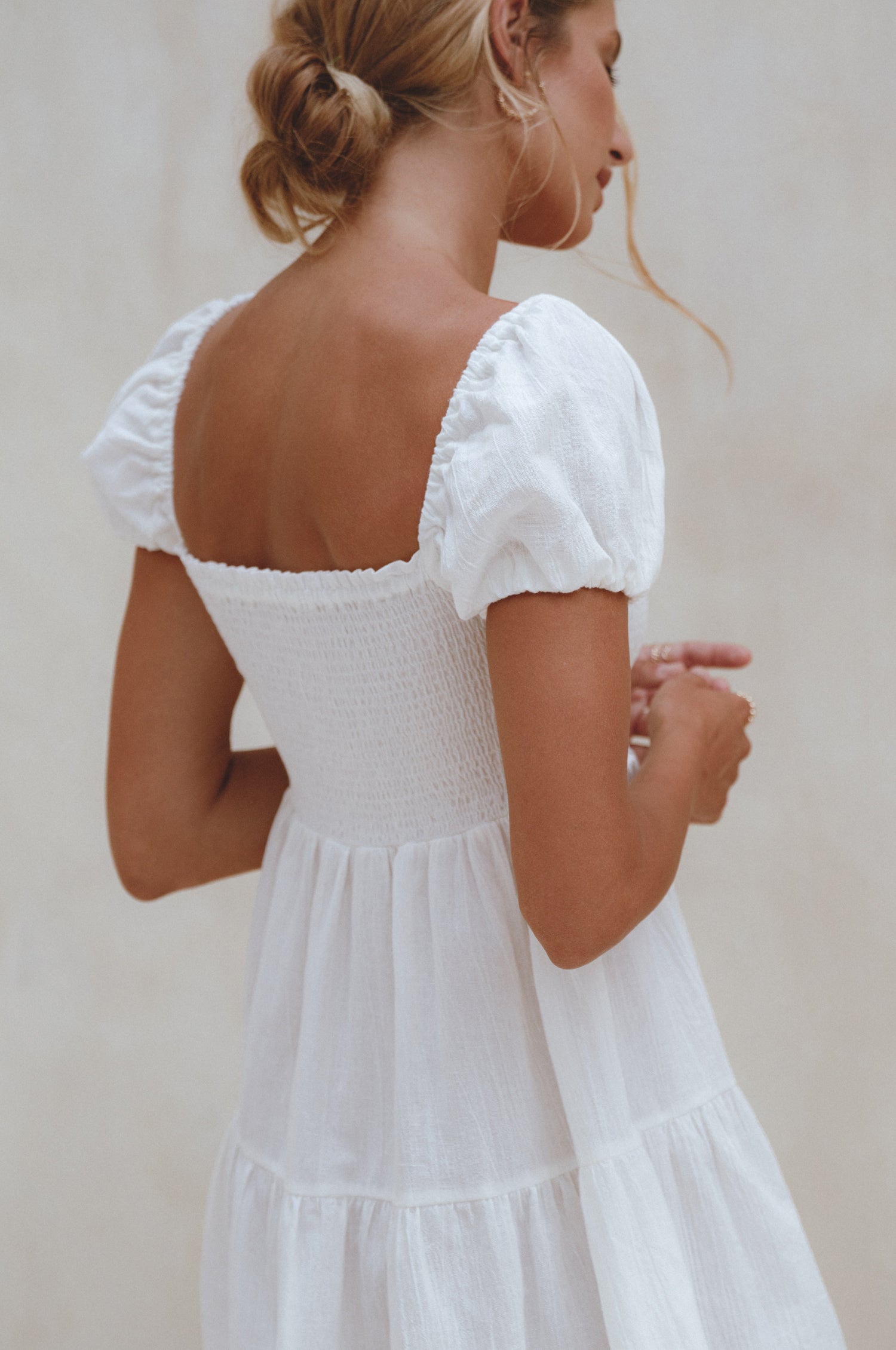 A stylish Catalina Smocked Linen Mini Dress featuring a smocked bodice, ruffles, and petite shell buttons, made from breathable organic linen.