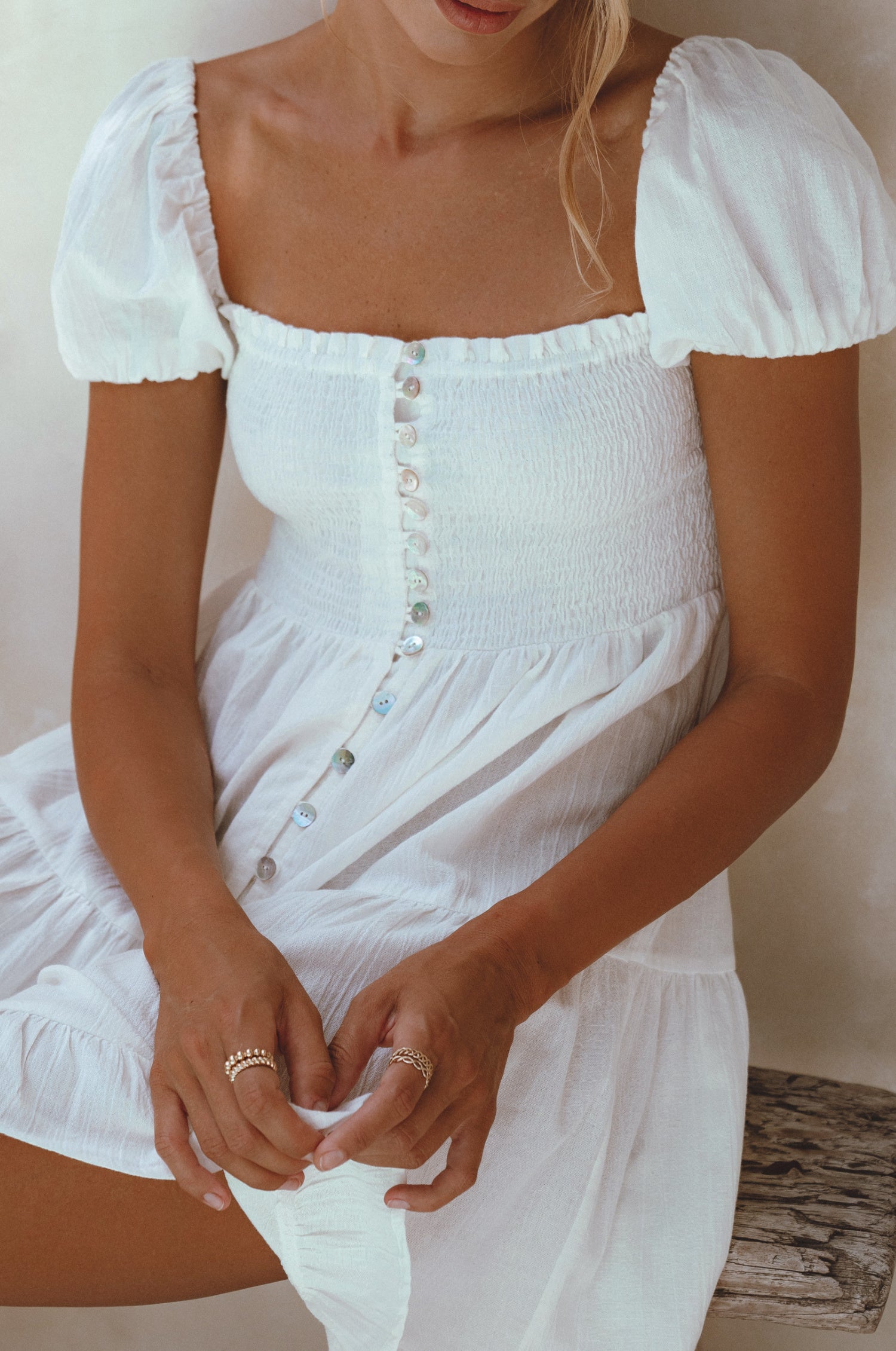 A stylish Catalina Smocked Linen Mini Dress featuring a smocked bodice, ruffles, and petite shell buttons, made from breathable organic linen.