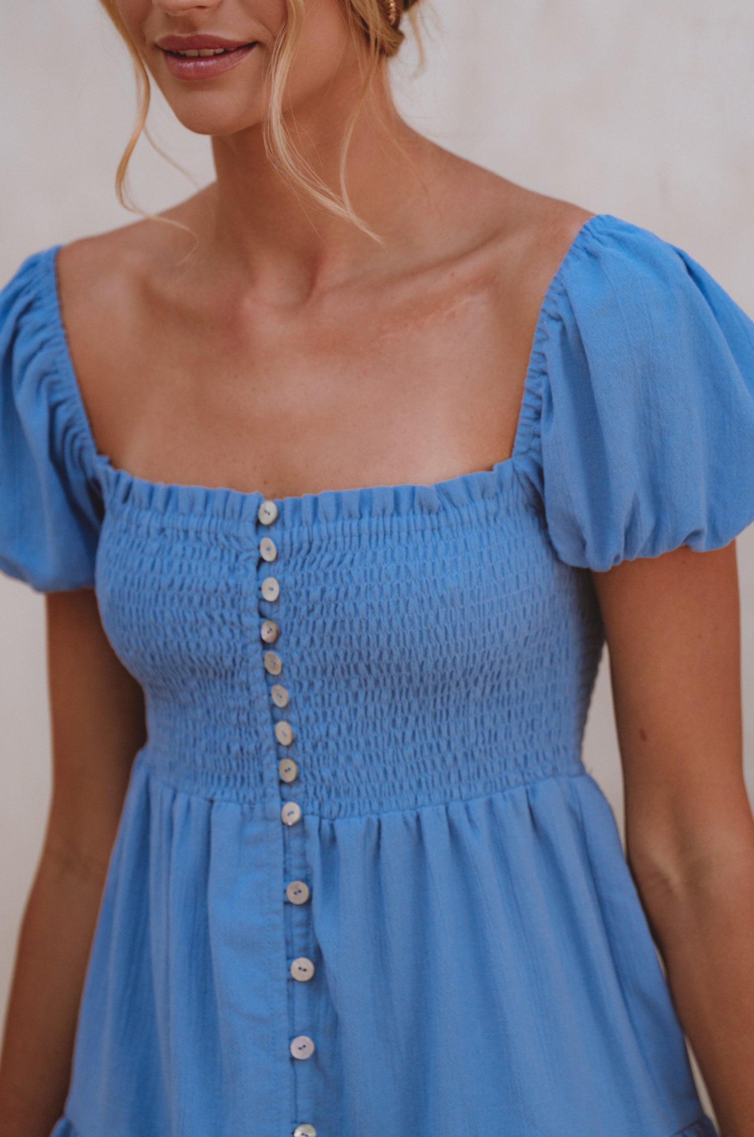 Catalina Smocked Linen Mini Dress featuring a smocked bodice, ruffles, and petite shell buttons in a summery color.