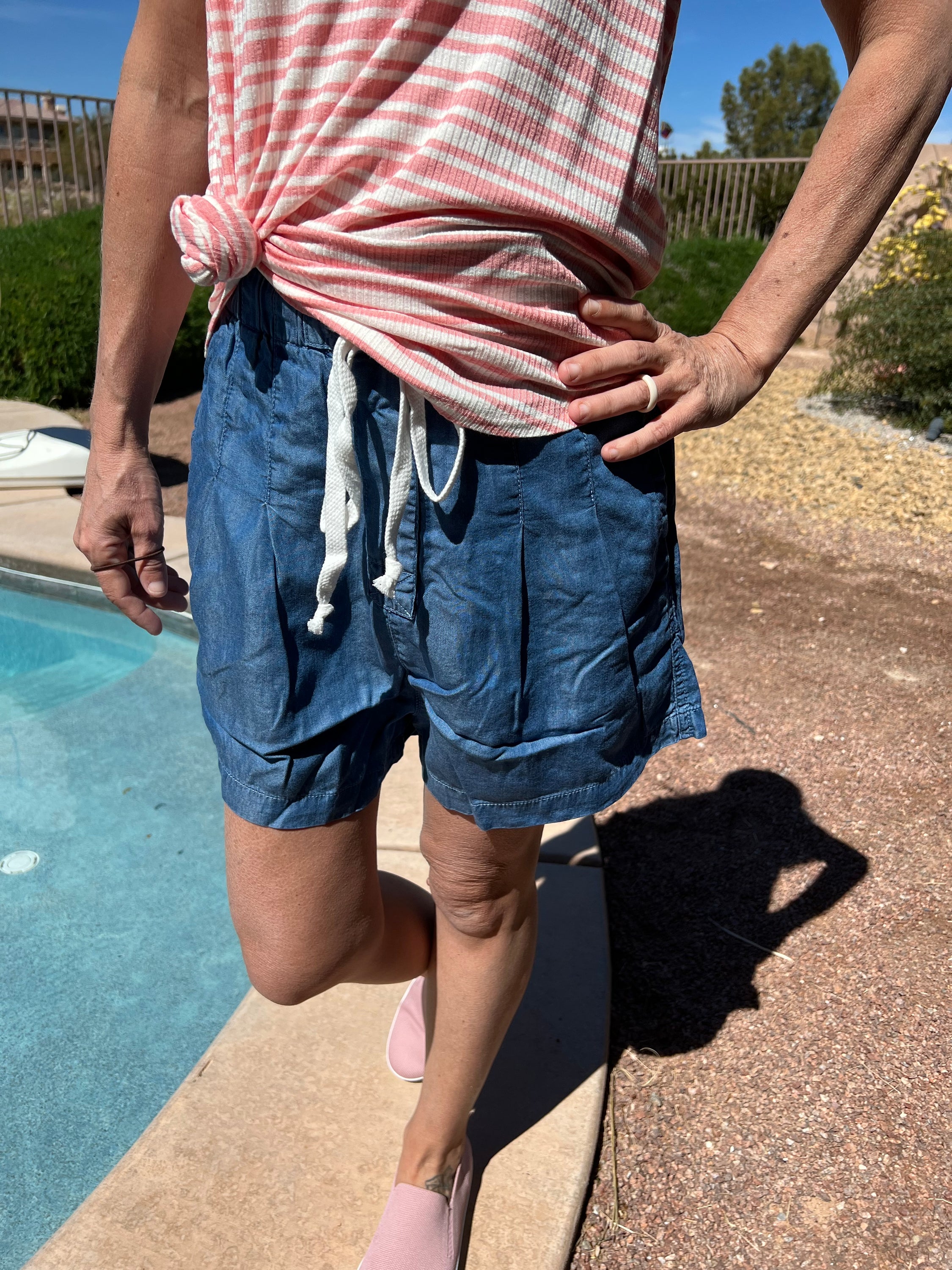 Chambray drawstring ruffle waist shorts featuring pleated sides and pockets, perfect for summer wear.