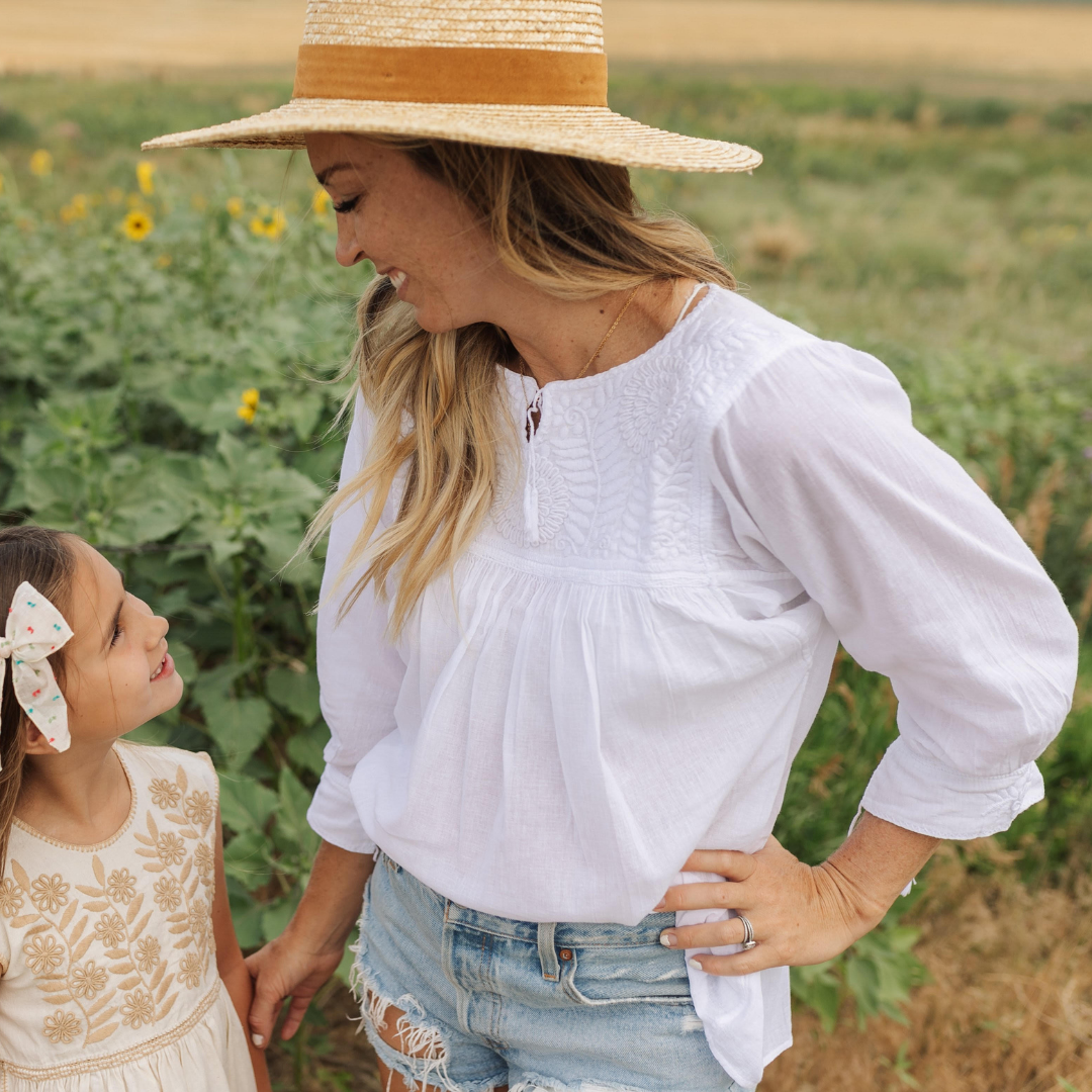 Chaya Blouse featuring white cotton fabric with intricate hand embroidery and tassel details on sleeves.