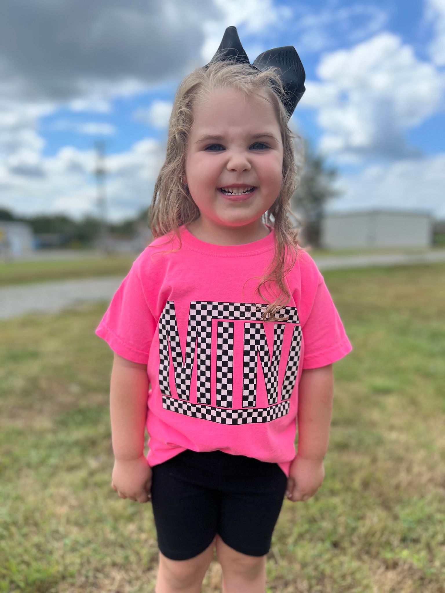 A vibrant neon pink checkered mini tee for youth, showcasing a stylish design perfect for matching outfits.