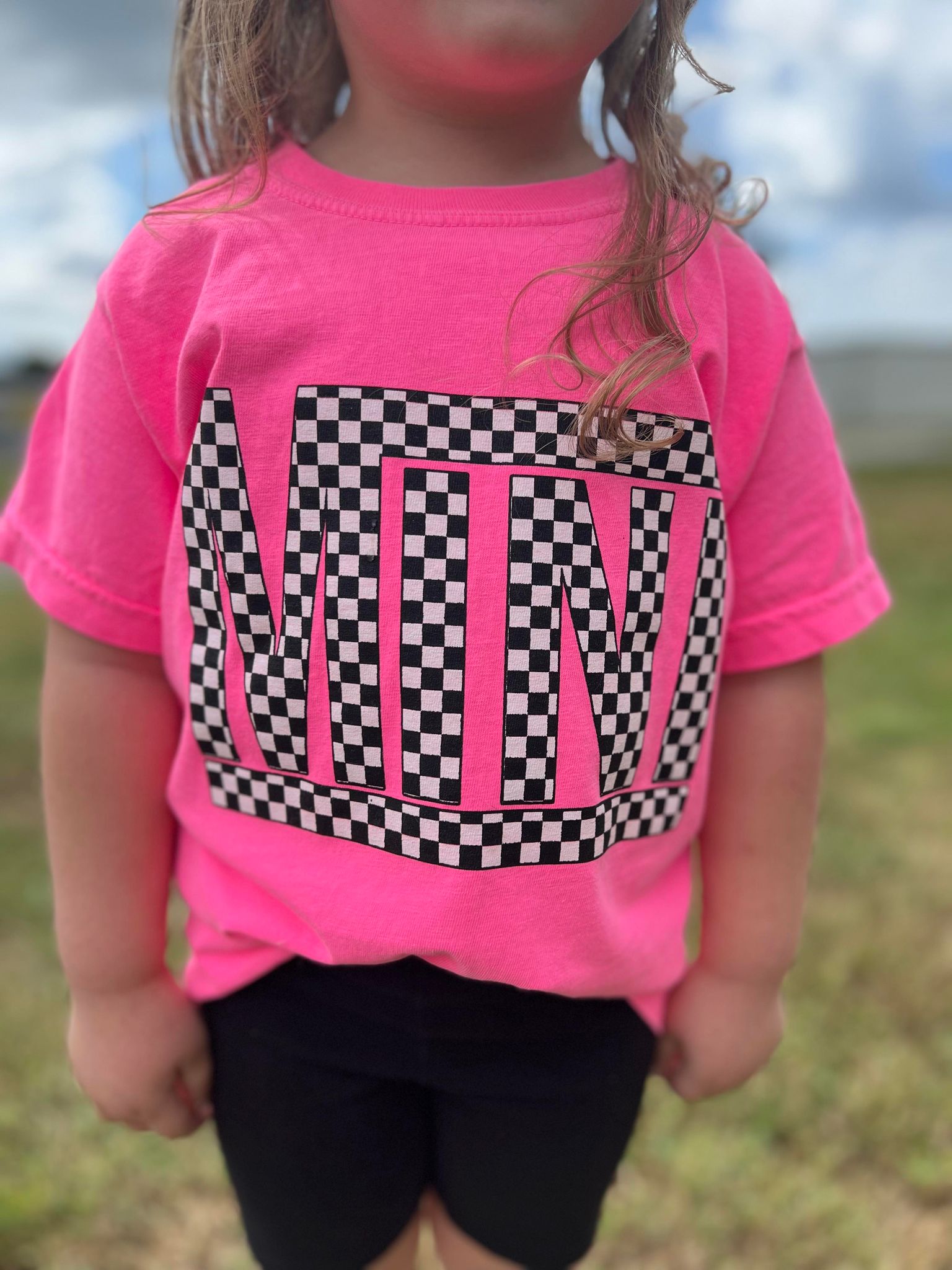 A vibrant neon pink checkered mini tee for youth, showcasing a stylish design perfect for matching outfits.