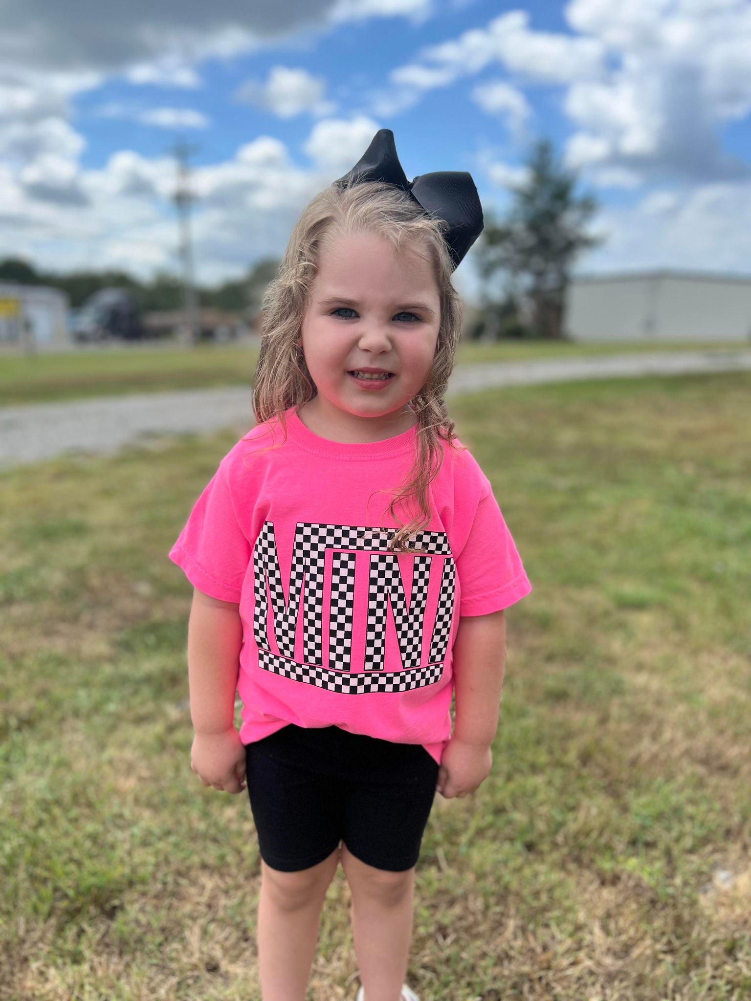 A vibrant neon pink checkered mini tee for youth, showcasing a stylish design perfect for matching outfits.