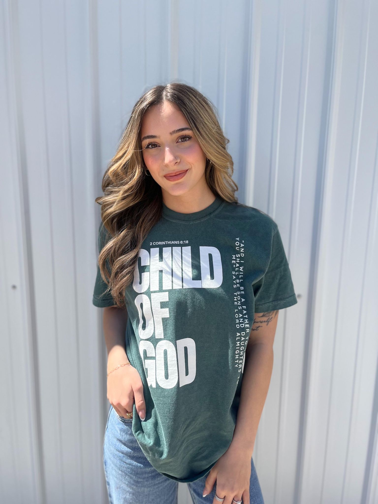 A stylish blue spruce Child of God Tee made from 100% cotton, featuring a bold screen-printed design.