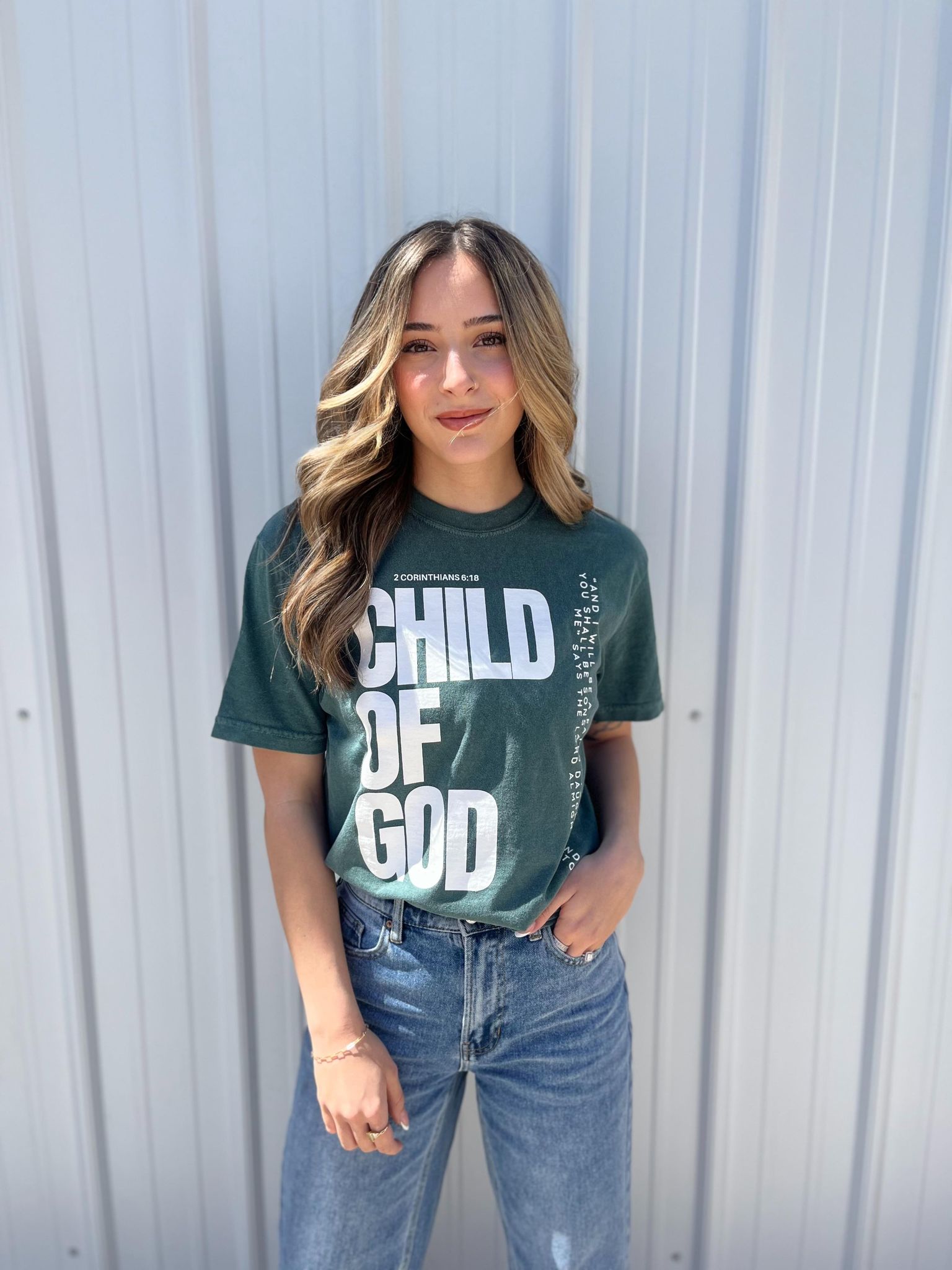 A stylish blue spruce Child of God Tee made from 100% cotton, featuring a bold screen-printed design.