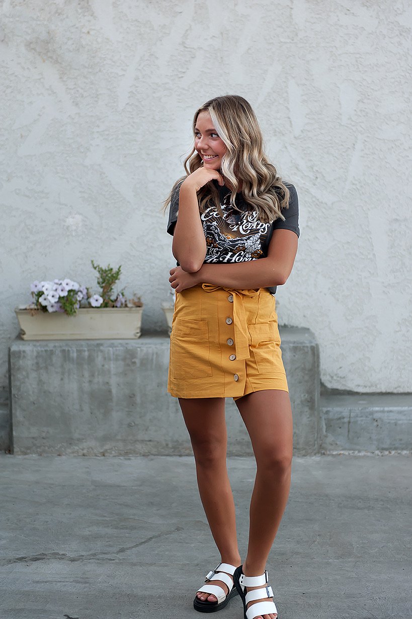 Coconut Button Solid Woven Skirt in Mustard with belt and accent pockets, displayed on a model.