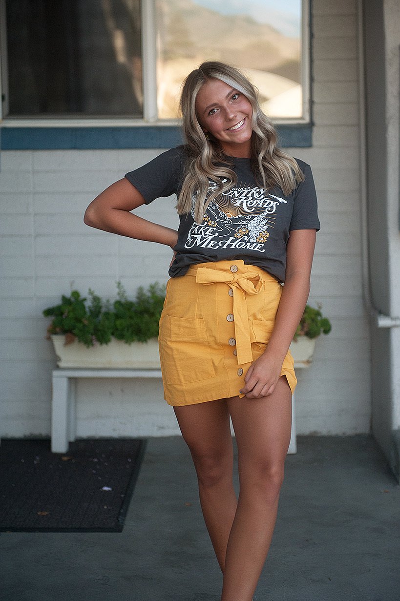 Coconut Button Solid Woven Skirt in Mustard with belt and accent pockets, displayed on a model.