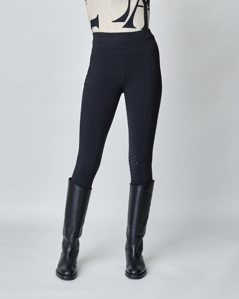 A pair of black compression pull-on breeches designed for equestrian riding, featuring a high waist and discreet mobile phone pocket.