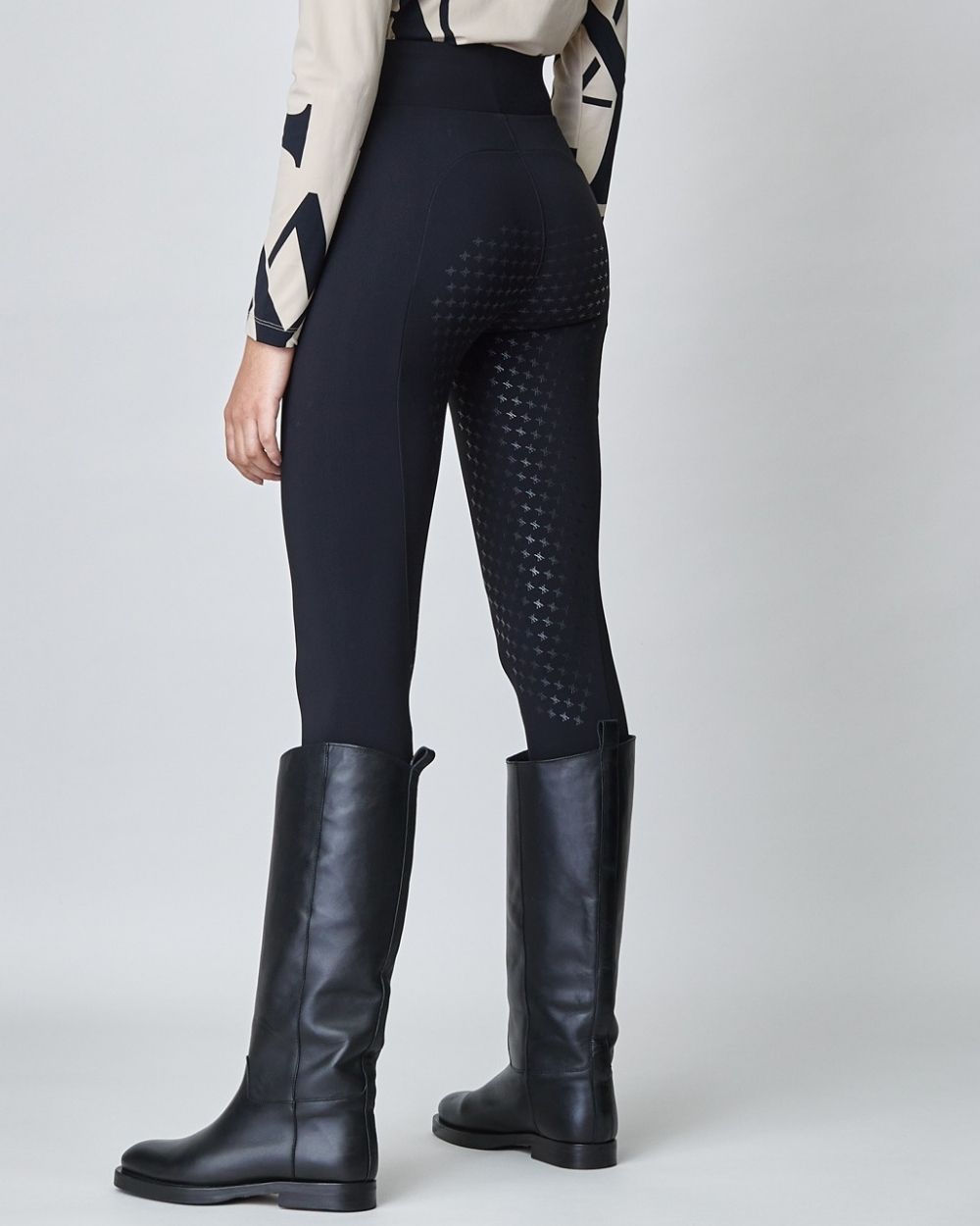 A pair of black compression pull-on breeches designed for equestrian riding, featuring a high waist and discreet mobile phone pocket.